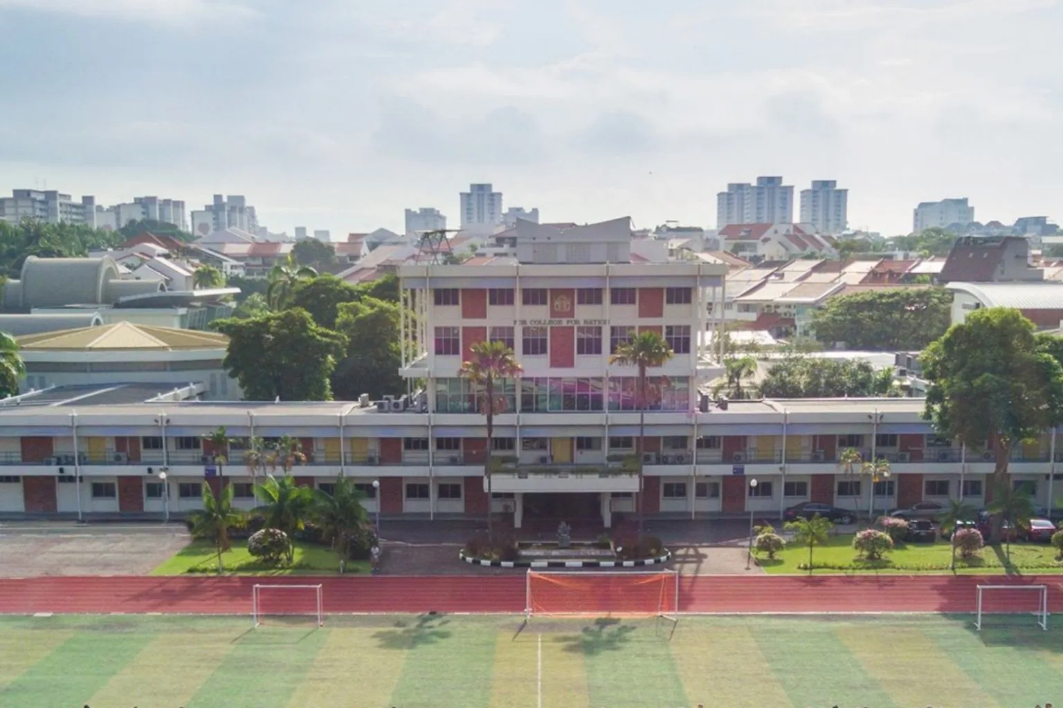 Temasek Junior College campus on Bedok South Road with its sports field in front and landed homes behind