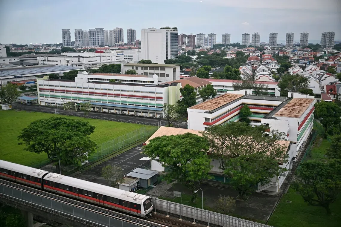 The former Temasek Primary and Temasek Secondary school buildings on the New Upper Changi Road GLS site, with an East-West Line train on the elevated viaduct in front and the Opera Estate landed homes behind